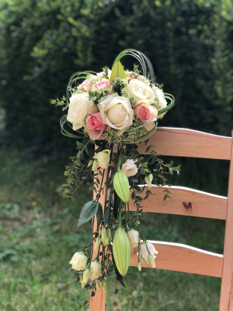 Bouquet de mariée retombant en cascade composé de roses blanches, roses roses et boutons de lys, idéal pour un mariage élégant à Bruxelles.