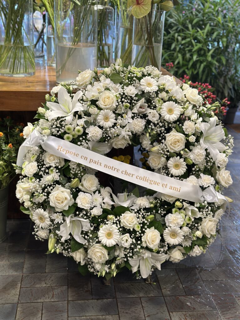 Couronne fun&eacute;raire de fleurs blanches avec roses, lys et gerberas, accompagn&eacute;e d'un ruban personnalis&eacute; &mdash; Gladys Fleurs Bruxelles