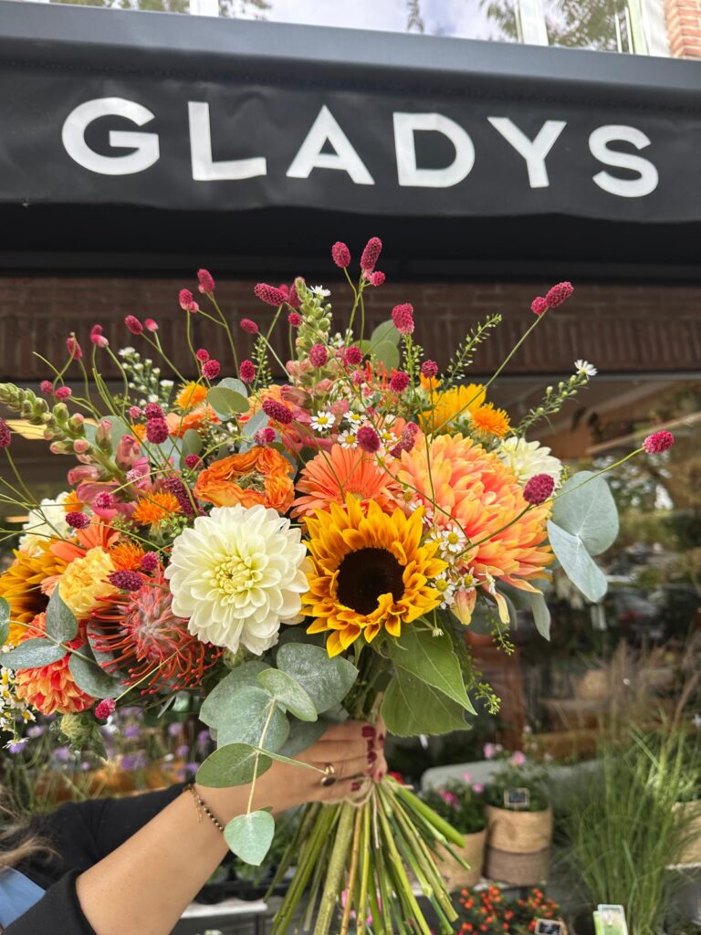Bouquet de fleurs coloré avec tournesol et dahlias devant la boutique Gladys Fleurs à Bruxelles.